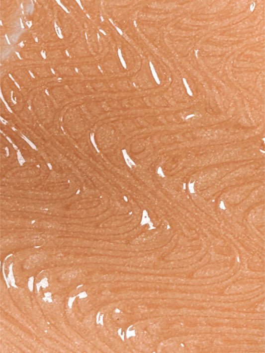 A close-up of a fingerprint pattern on human skin with a shiny, reflective surface, possibly enhanced by Bodyography Radiant Glow Primer + Niacinamide for a luminous finish.