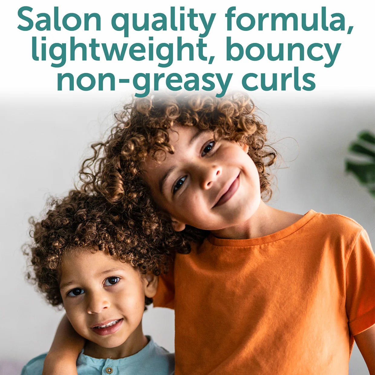 Two smiling kids with curly hair stand close, one in an orange shirt with their arm around the other in teal. Text above: Fairy Tales Curly-Q Kids Refresher Spray for Curly Hair 8 oz—lightweight formula for bouncy curls and frizz control.