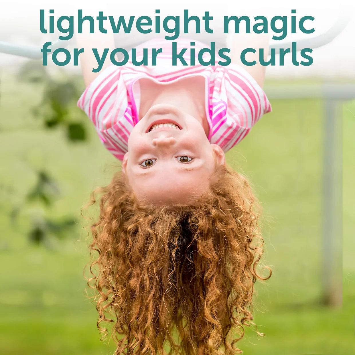 A joyful curly-haired child hangs upside down on playground bars in a pink striped shirt. Text reads: Fairy Tales Curly-Q Kids Refresher Spray for Curly Hair 8 oz—lightweight magic for your kids curls. Soft, blurry green background.