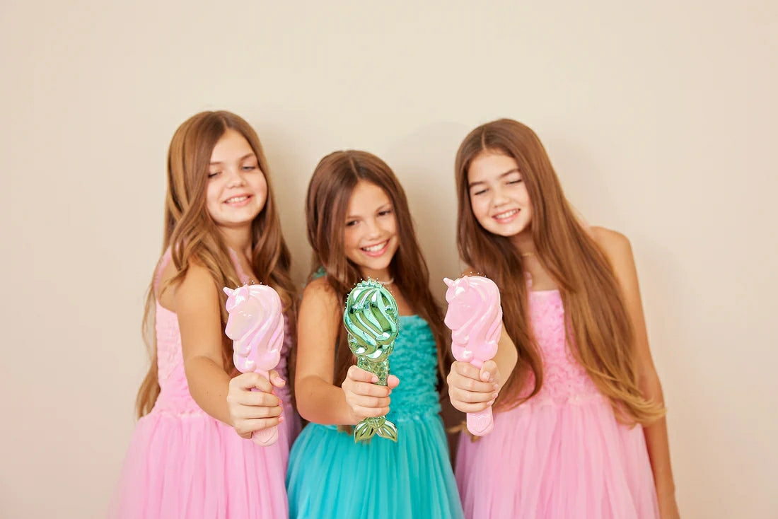 Three girls in colorful dresses holding a mermaid detangling hair brush for easy styling