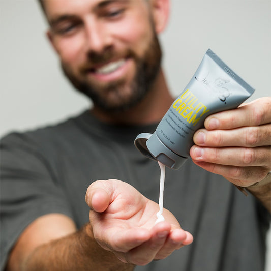 Man applying Johnny B leave-in conditioner from a tube to his palm for smooth styling