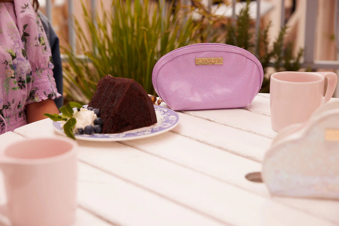 Glimmer Wish mermaid purple pearl pouch on a table next to dessert and beverages