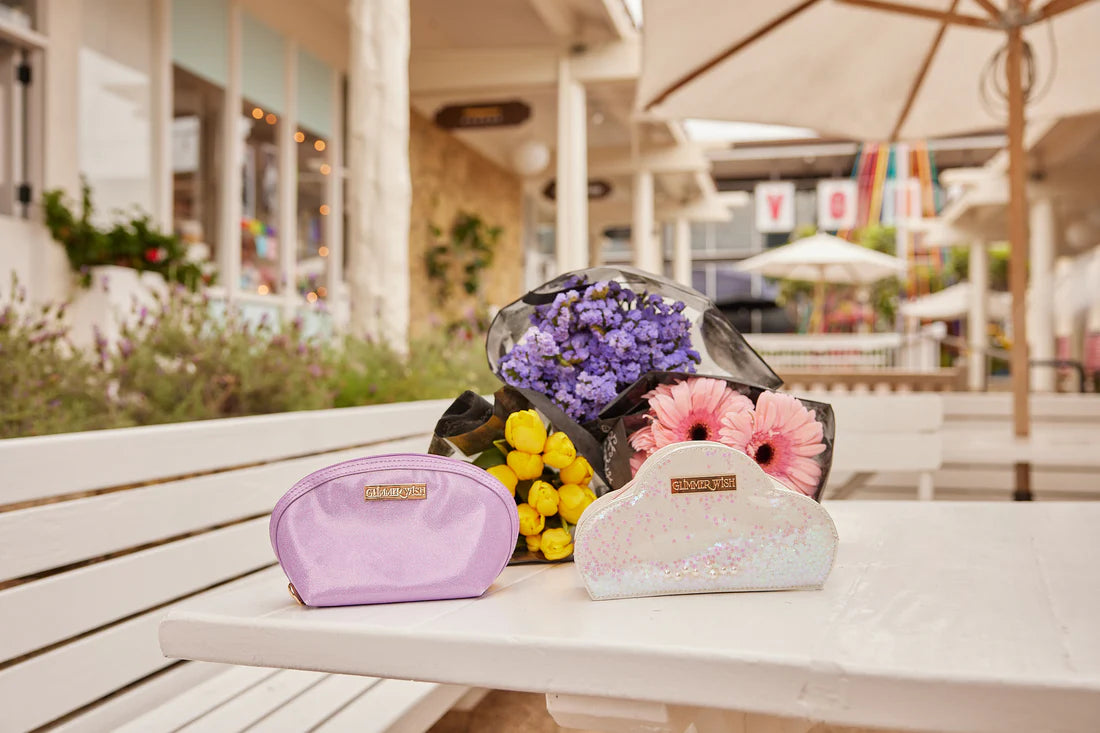 Glimmer Wish Mermaid Purple Pearl Pouch on a table with colorful flowers in the background