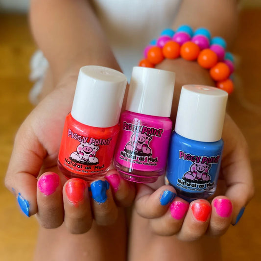Piggy Paint Color Splash Gift Set featuring vibrant nail polishes in red, pink, and blue held in hands