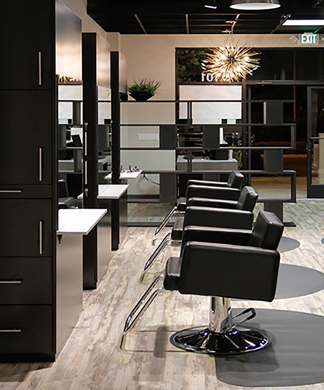 3x4 anti-fatigue mat for salons under black styling chairs in a modern salon with wood flooring and mirrors