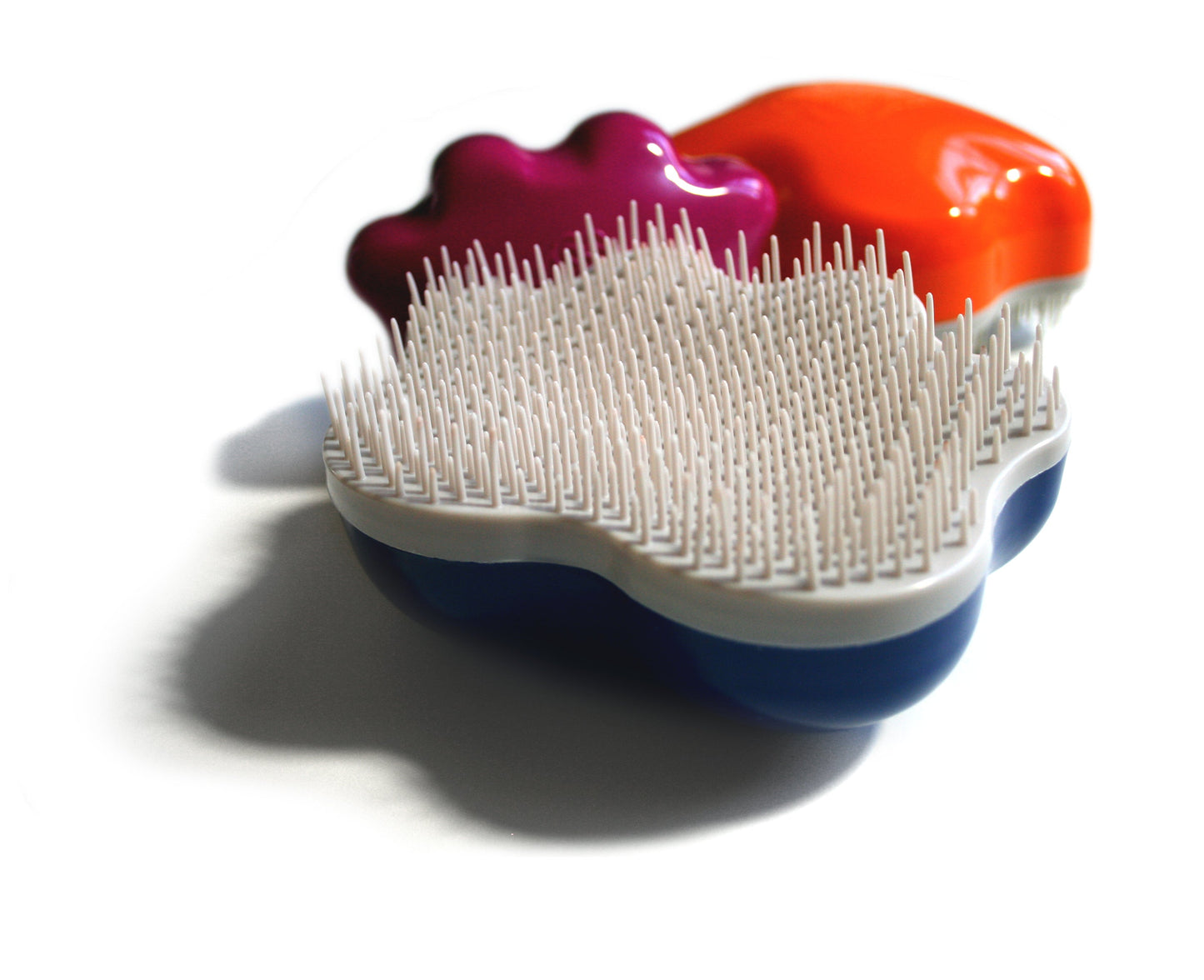 A vibrant Groom Genie Original Pet Detangling Brush with abstract shape and unique white bristles in purple, orange, blue, and white sections, displayed on a white background.