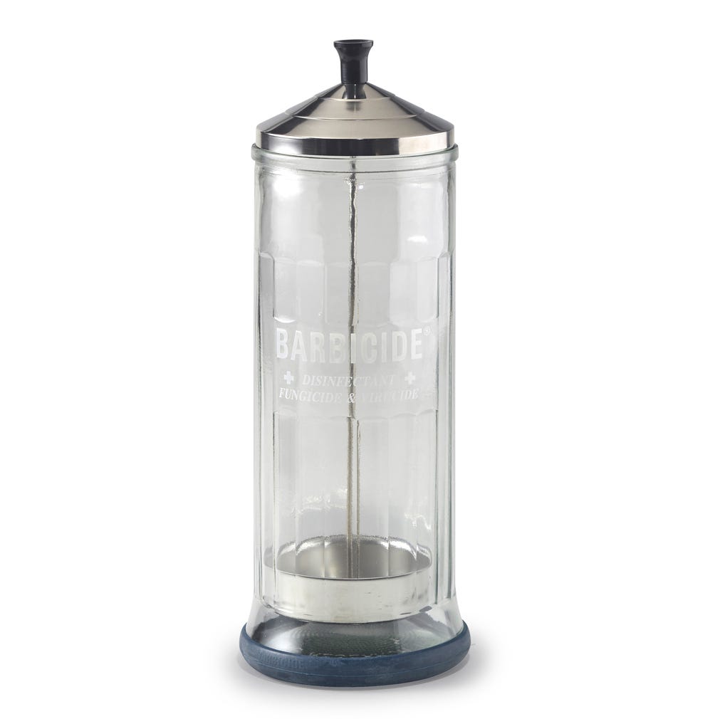 The Barbicide Jar - Large is a tall, faceted glass jar with a metal lid, blue base, and inner metal basket. Used in barbershops for disinfecting tools, it displays the word Barbicide on the front.