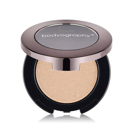 A round compact of Bodyography Highlighter Pressed Powder Sunsculpt Duo -Bronzer/Highlighter with a metallic lid, clear center, and radiant light beige powder inside, shown on a white background.