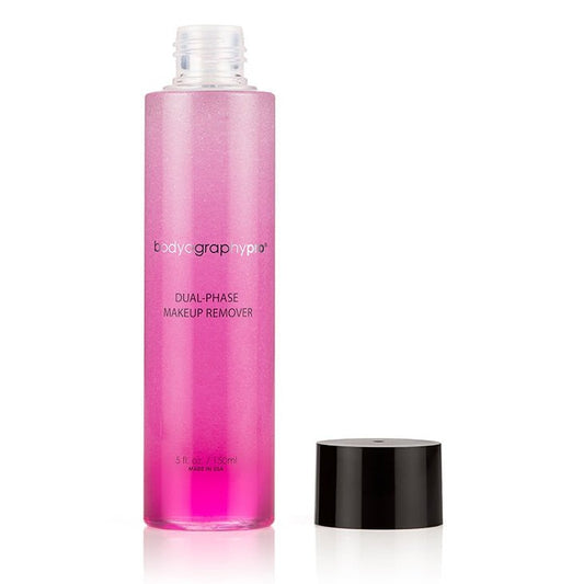 A tall, clear bottle of Bodyography Pro Dual-Phase Makeup Remover with pink liquid stands upright on a white background, its black cap beside it, promising to gently dissolve waterproof makeup for all skin types.