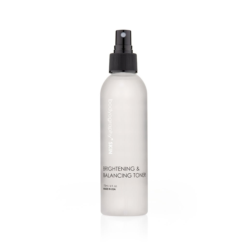 A white spray bottle with a black nozzle, labeled Bodyography Skin Care Brightening & Balancing Toner 6 oz, stands upright against a plain white background.