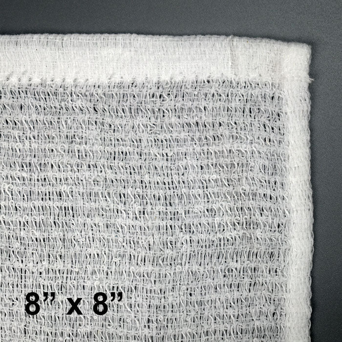Close-up of a White Towel Services Starter Kit cotton towel (8x8), textured and soft like 100% cotton, shown on a gray surface. 8 x 8 appears in bold black at the bottom left. Includes 500 towels and deluxe warmer.