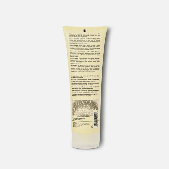A yellow tube of Hempz Herbal Body Wash Age Defying Scent 8.5 fl.oz. is shown from the back, featuring dense black product info and a barcode near the bottom, set against a plain white background.