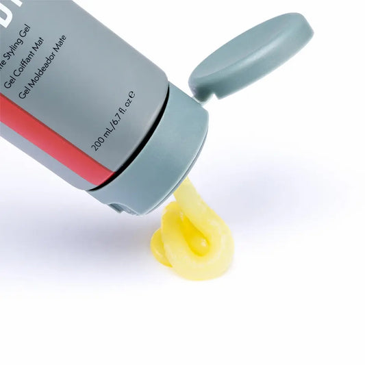 Johnny B Fuddy Matte Gel in a gray bottle with a yellow gel oozing from the nozzle
