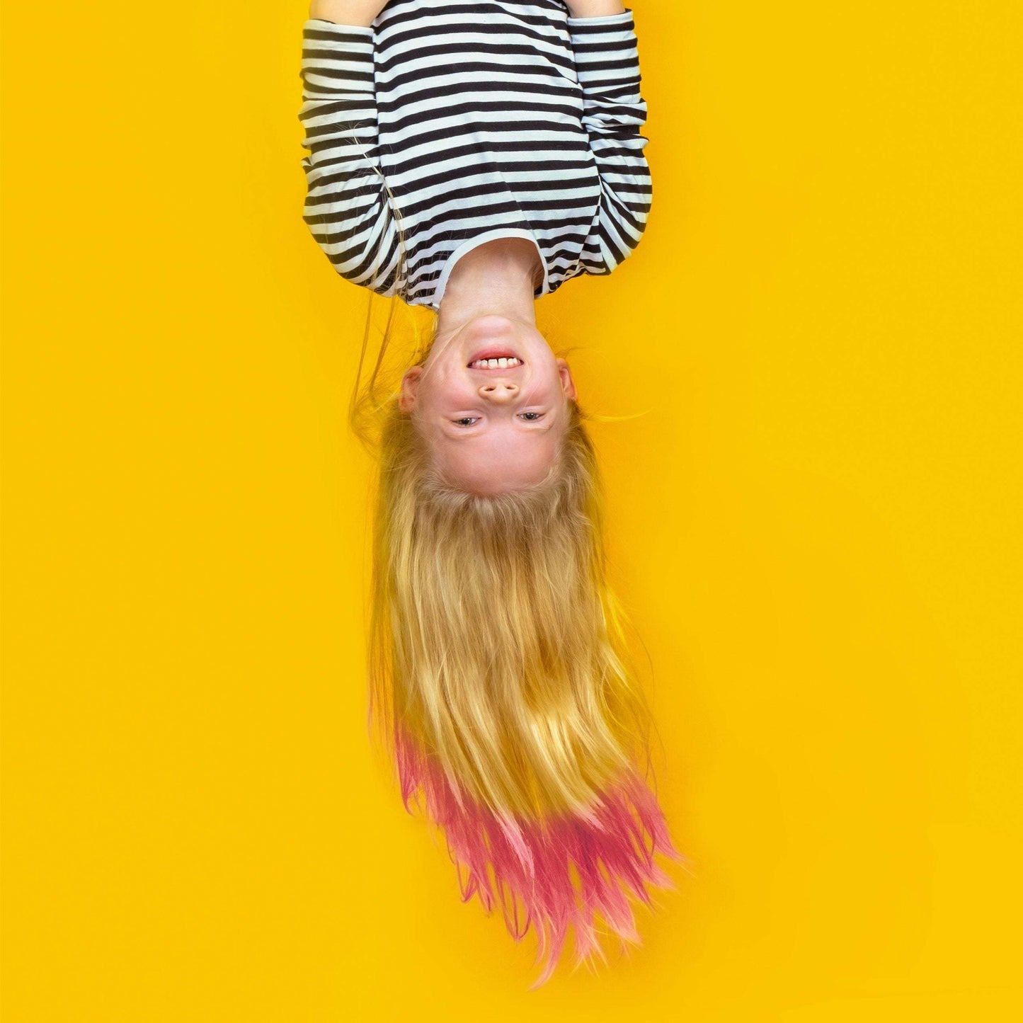 Child with blonde hair featuring pink highlights enjoying a vibrant yellow background with playful vibes