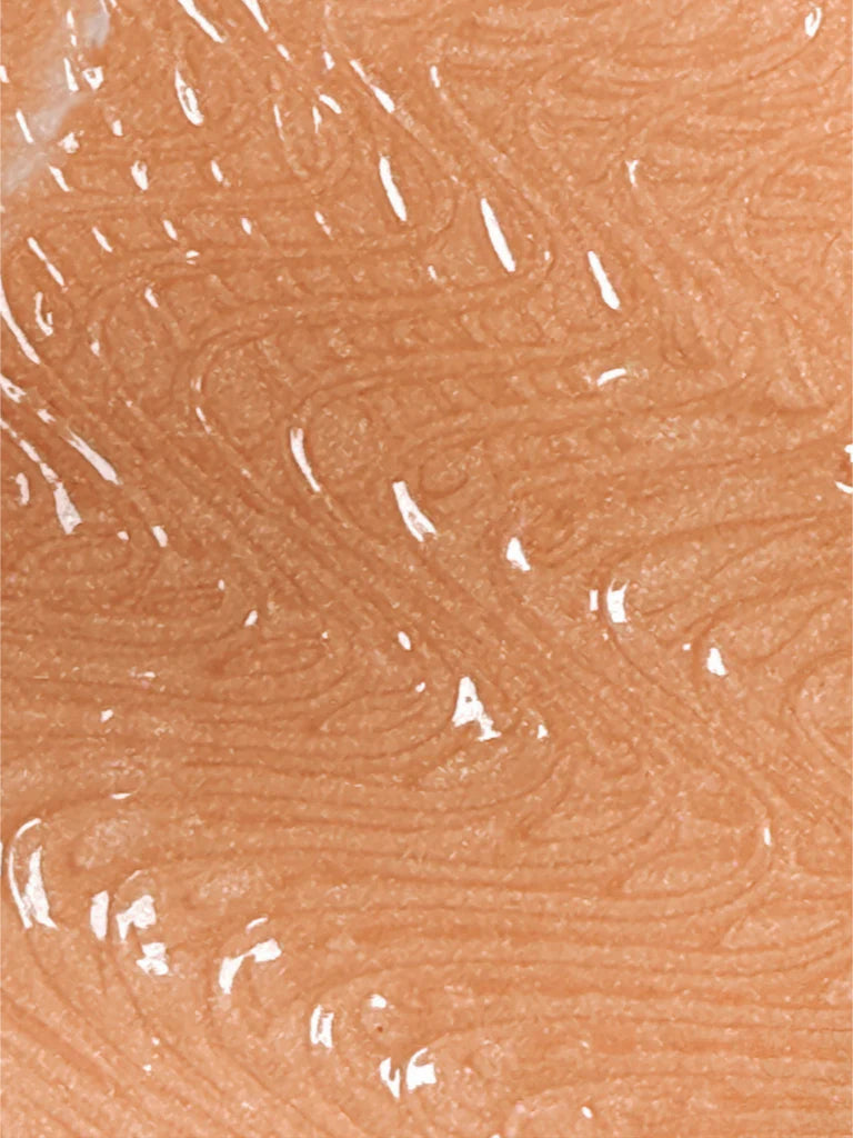 A close-up of a fingerprint pattern on human skin with a shiny, reflective surface, possibly enhanced by Bodyography Radiant Glow Primer + Niacinamide for a luminous finish.