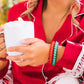 Teleties Christmas hair ties in red and green worn by a woman holding a mug of hot cocoa