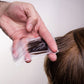 Seki Edge end papers used for hair coloring, showing a hand holding a paper against brown hair