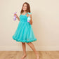 Girl wearing a turquoise dress, holding Glimmer Wish Mermaid Conditioner in each hand, smiling happily