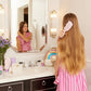 Little girl brushing long hair in bathroom using unicorn shampoo for kids with a playful look