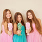 Three girls in colorful dresses holding a mermaid detangling hair brush for easy styling