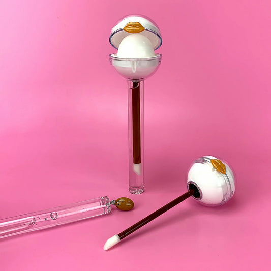 Glossy Pops Tropical Coconut Lip Balm in fun packaging with applicator and gloss tube on pink background