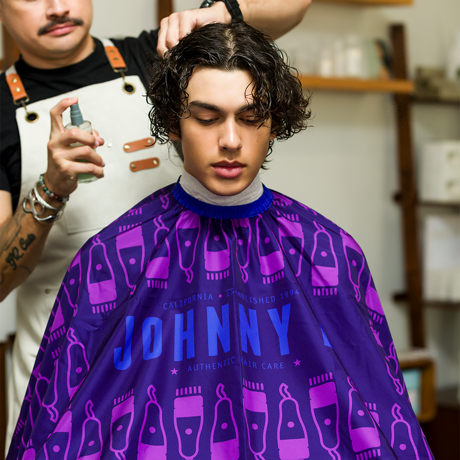 Johnny B. cutting cape in purple with iconic design for professional haircuts and styling