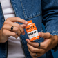 Johnny B Hold Up Hair Powder in an orange container with a person holding it stylishly