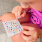 Child applying Piggy Paint nail art stickers featuring colorful designs for creative nail decoration