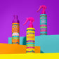 Piggy Paint pineapple banana hair detangler spray next to shampoo and conditioner on colorful backdrop