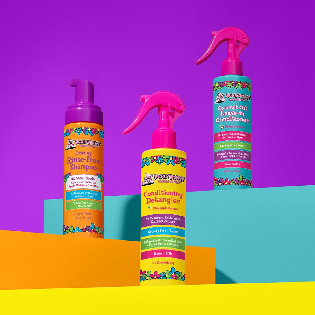 Piggy Paint pineapple banana hair detangler spray next to shampoo and conditioner on colorful backdrop