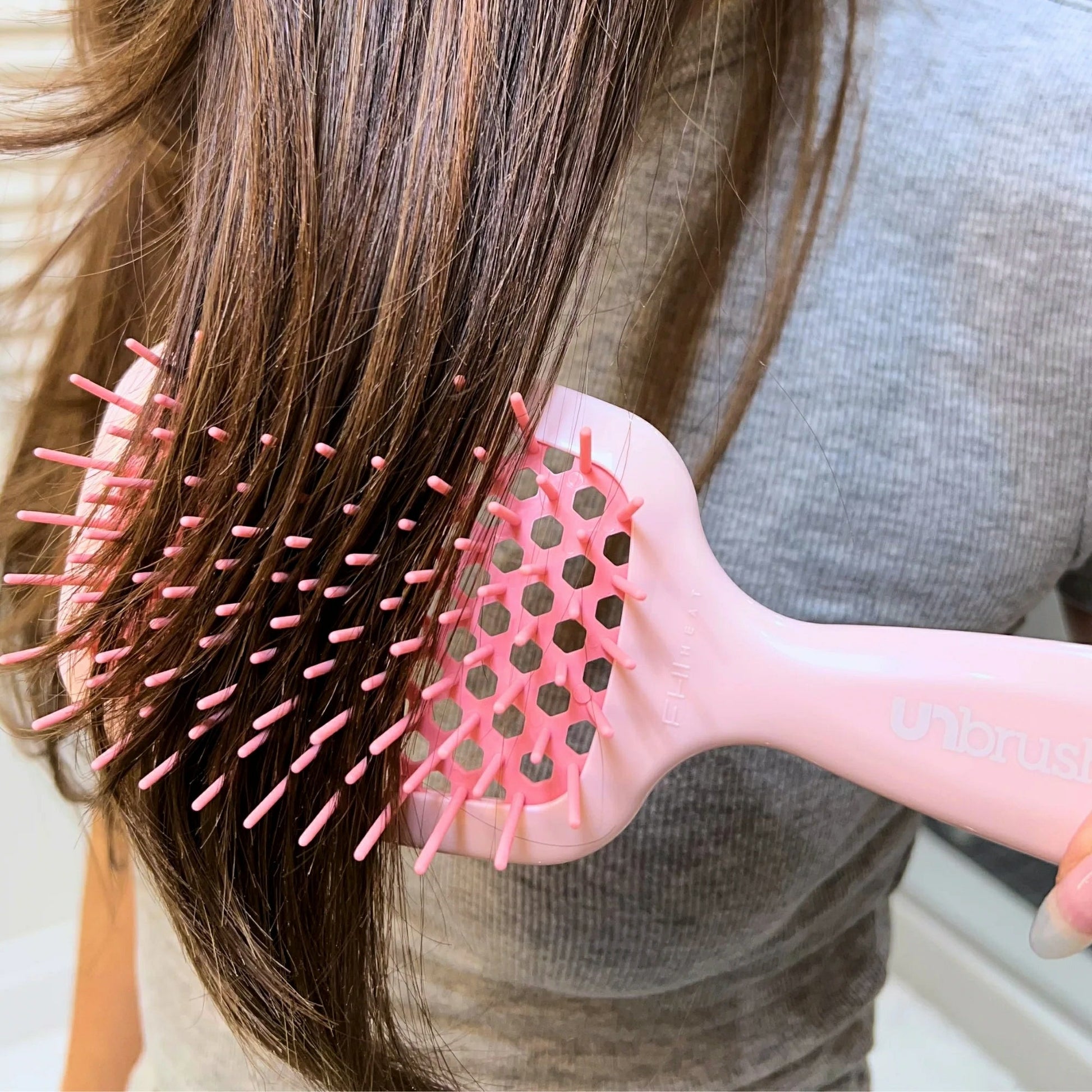 Unbrush detangling hair brush in pink, gently smoothing through long hair strands for effortless detangling