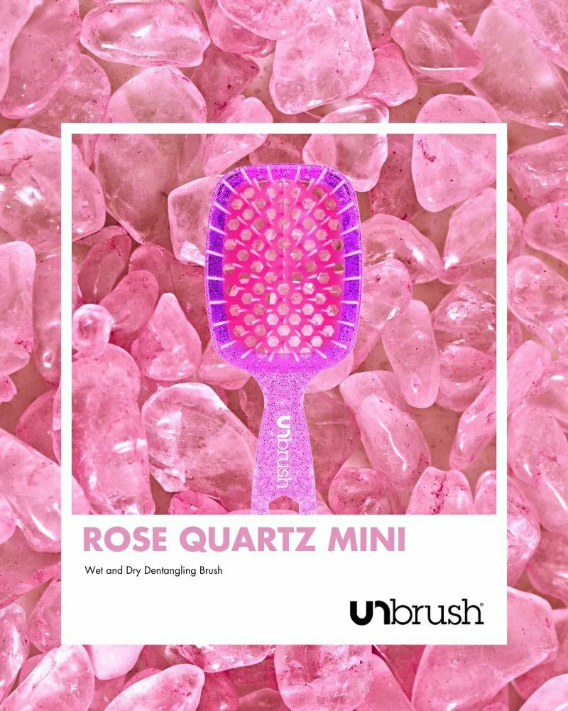 Unbrush Rose Quartz mini detangling hair brush on a bed of pink quartz stones