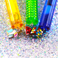Glossy Pops TGI Fruity lip balm tubes in vibrant colors with fun charms for fruity hydration