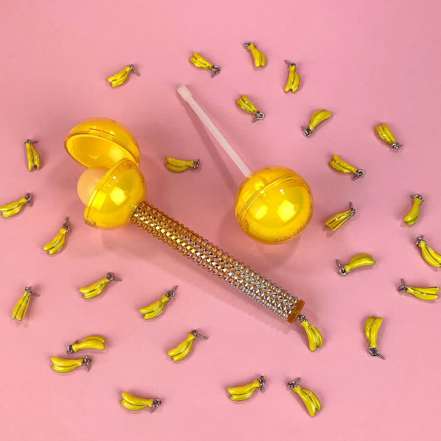 Glossy Pops TGI Fruity lip balm in yellow packaging with banana motif for vibrant lip hydration