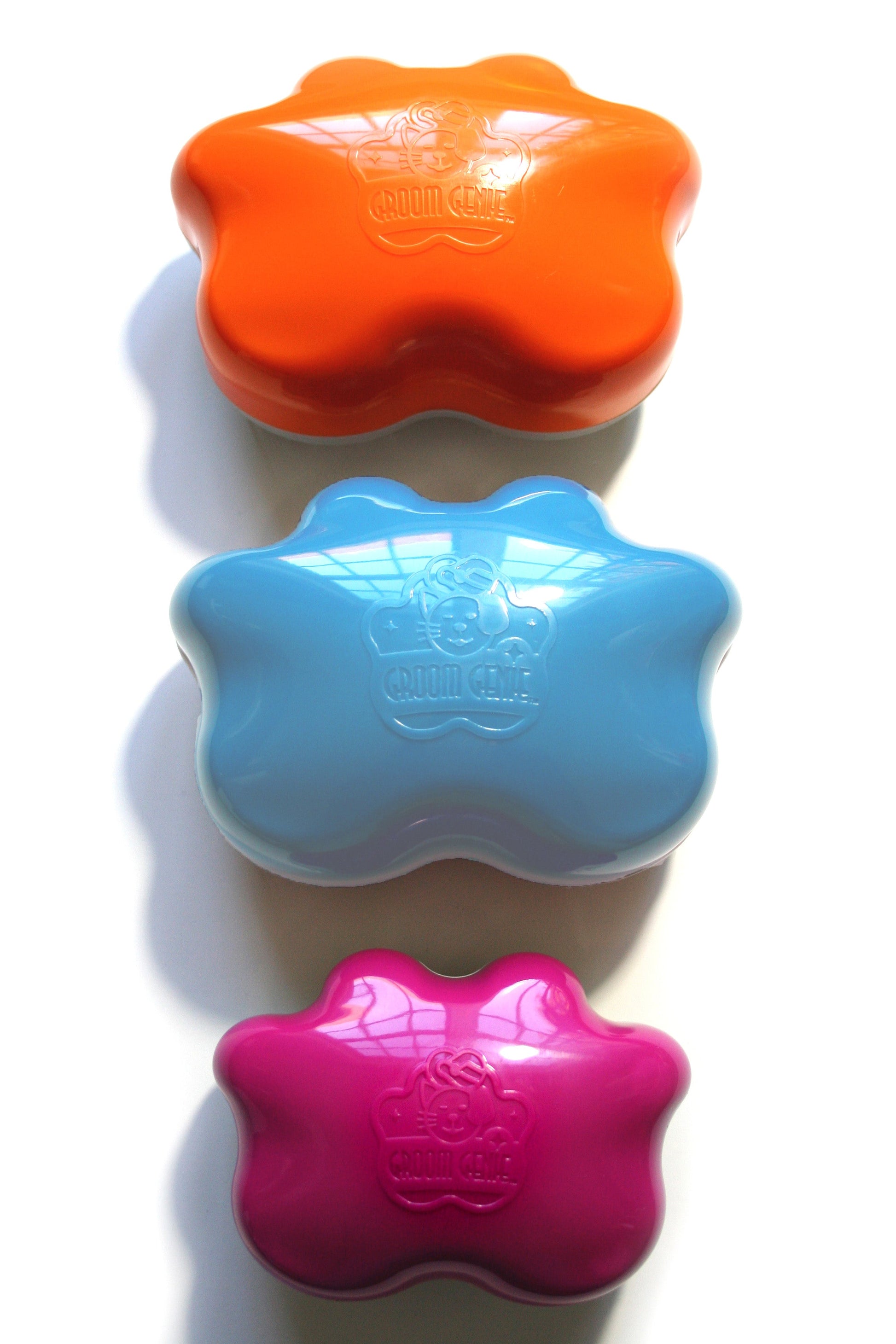 Set of three Groom Genie pet detangling brush in orange, blue, and pink colors for easy grooming