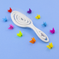 Knot Genie Detangling Brush in White with Spiral Design, surrounded by colorful hair clips