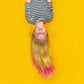 Child with blonde hair featuring pink highlights enjoying a vibrant yellow background with playful vibes
