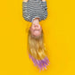 Girl with long blonde hair featuring purple hair color conditioner tips against a bright yellow background