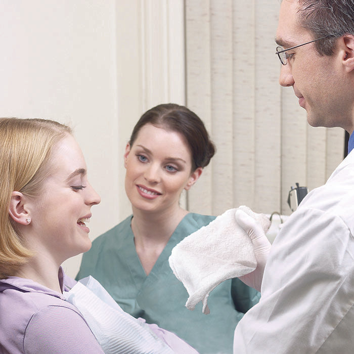 Medical professional offering a soft towel to a patient post-treatment, highlighting the use of refreshment towels in clinics.