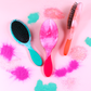 Three Wet Brush Color Shock detanglers in vibrant colors with a playful background of colorful glitter