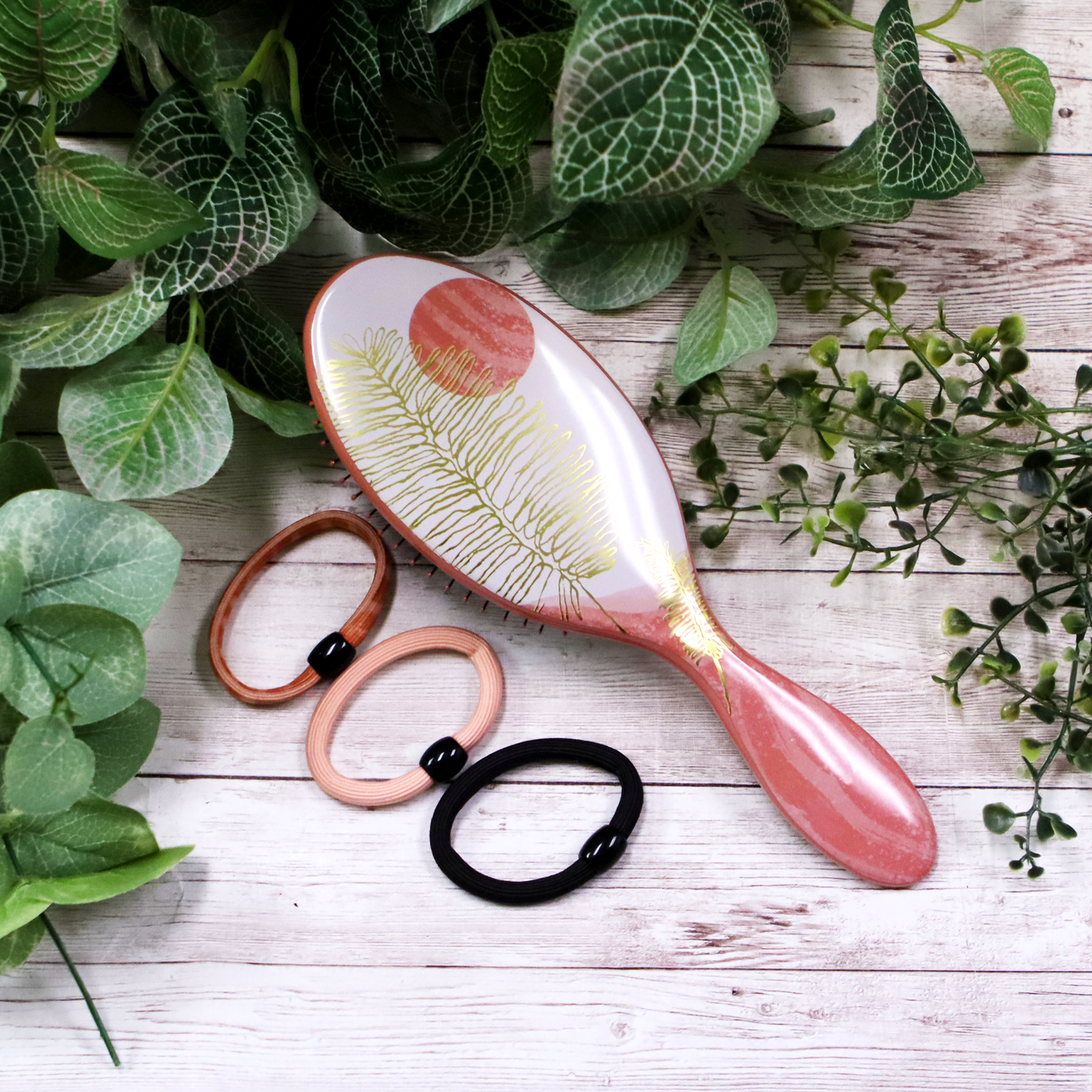 Wet Brush Pro Tranquil Beauty Kit featuring a paddle brush and hair ties surrounded by greenery